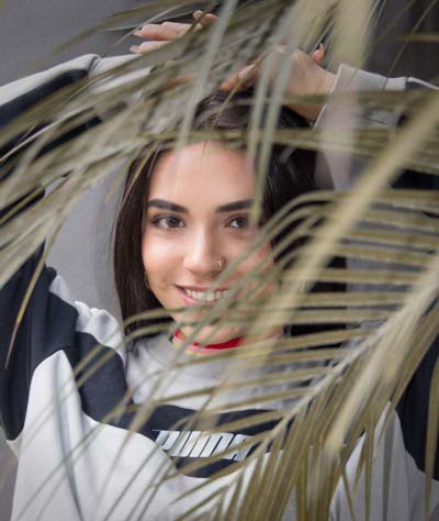 A photo of a Latina woman posing behind a plant